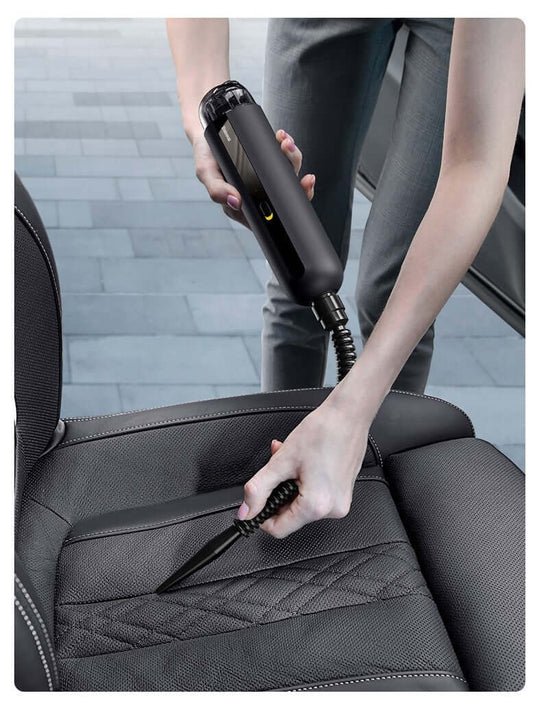 Person using a portable wireless car vacuum cleaner to clean car upholstery.